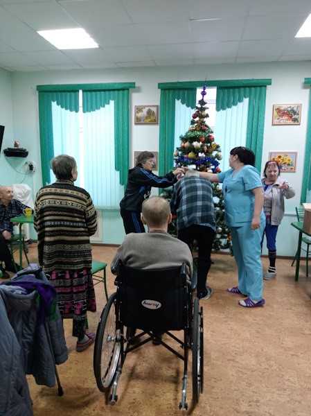 Получатели социальных услуг и сотрудники наряжают новогоднюю красавицу.